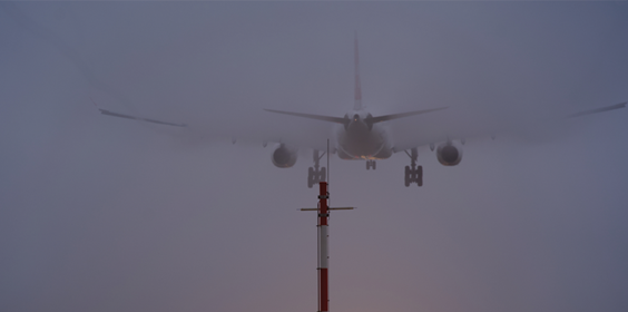 Landing Airplane With Spotlights At Runway Of The Airport On A Foggy Winter Day.