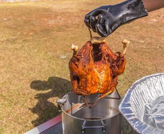 Fried Turkey Being Lifted Fresh From The Peanut Oil Or Hot Grease